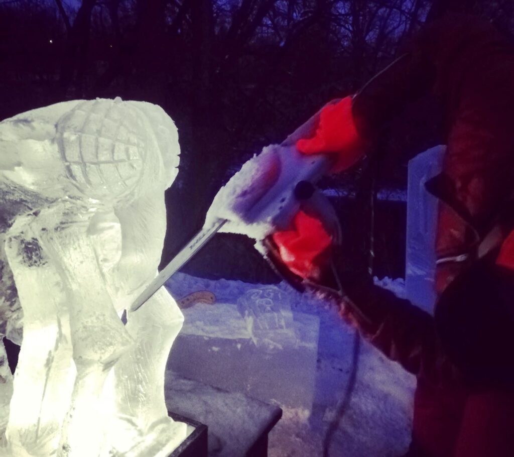 Un homme sculpte un bloc de glace avec une scie en hiver à la tombée du jour.